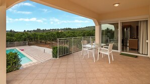 Un balcón con piscina, mobiliario exterior y vistas a viñedos.