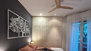 Un dormitorio moderno con cama, ventilador de techo y ventana con cortinas.