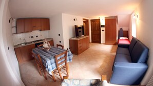 Un espacio habitable compacto con comedor, kitchenette y sofá.