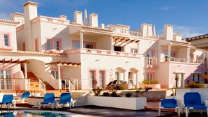 A hotel with a pool area, multiple balconies, and a staircase leading to the upper floors.