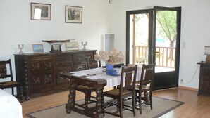 Un comedor con una mesa de madera, sillas, un jarrón con flores y un mueble con objetos decorativos.