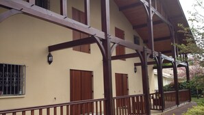 Un edificio con porche cubierto, vigas de madera y fachada color beige.