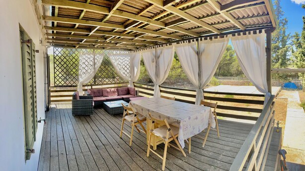 An outdoor covered patio with a table and chairs, a cushioned seating area, and a view of the surrounding landscape. - Peaceful holidays for an active family (Stari Grad)
