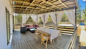 An outdoor covered patio with a table and chairs, a cushioned seating area, and a view of the surrounding landscape. - Peaceful holidays for an active family (Stari Grad)