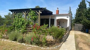 A house with a covered porch, a stone pathway, and a garden with various plants and flowers. - Peaceful holidays for an active family (Stari Grad)