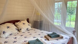 A bed with a canopy, floral bedding, and neatly folded towels. - 🌴 Creole house in the heart of the Martinique countryside (Gros-Morne)