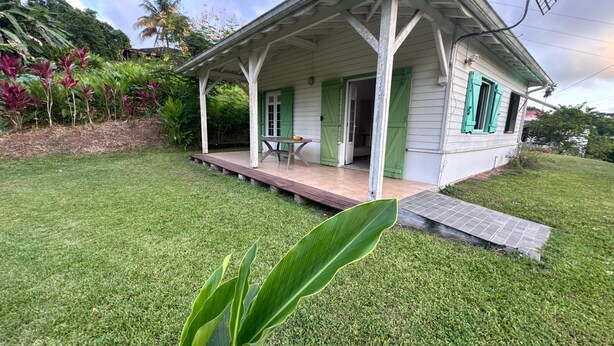 A house with a porch, green shutters, and a small table with a bowl. - 🌴 Creole house in the heart of the Martinique countryside (Gros-Morne)