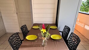 A covered patio with a table set for four, featuring yellow plates and a vase with flowers. - 🌴 Creole house in the heart of the Martinique countryside (Gros-Morne)
