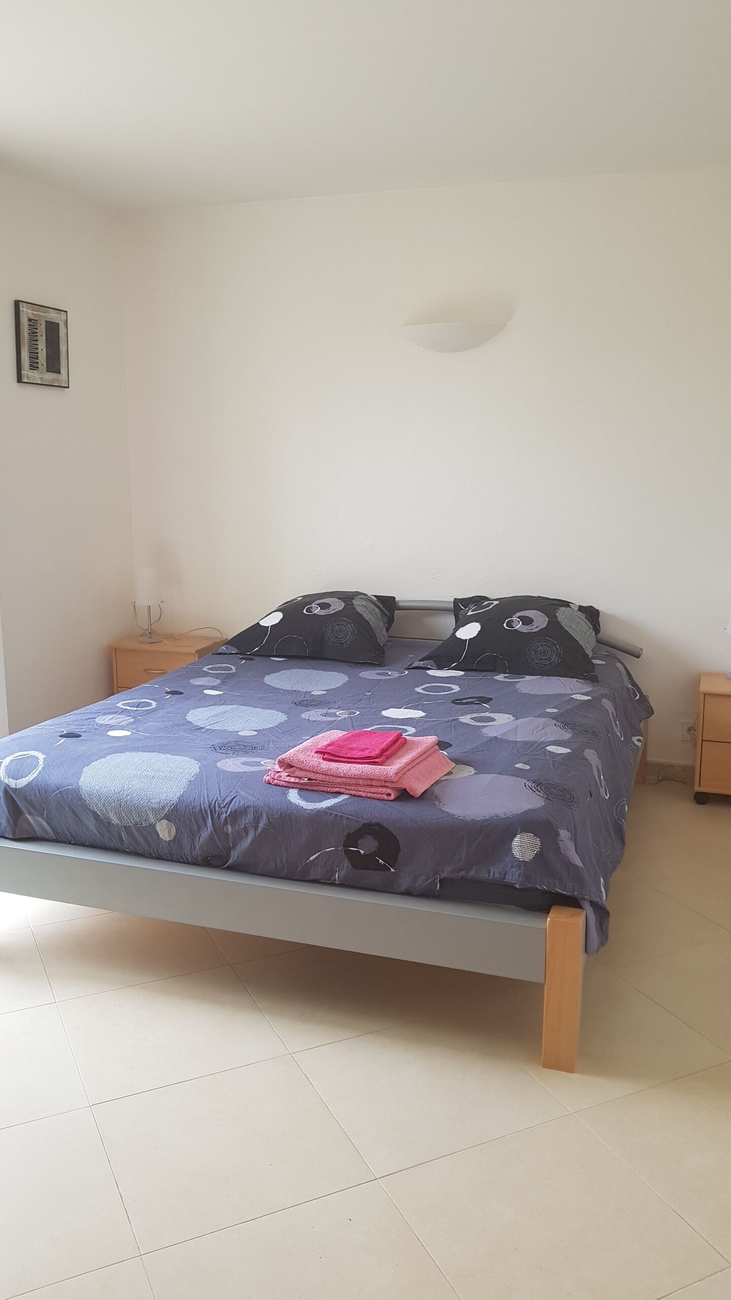 Una cama con un edredón estampado, dos almohadas y una toalla doblada sobre la cama.