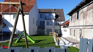 A residential area with a grassy yard, a swing set, and a wooden fence.