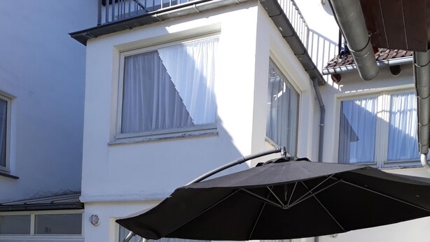 A patio area with a black umbrella, a concrete table, and a red cone.