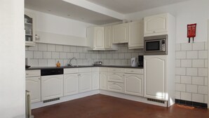 A kitchen with white cabinets, a microwave, and a coffee maker.
