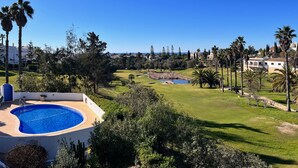 Une piscine entourée d’une végétation luxuriante et un parcours de golf.