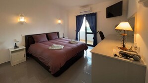 Une chambre à coucher avec un lit, des tables de chevet, un bureau avec une lampe et une fenêtre avec des rideaux.