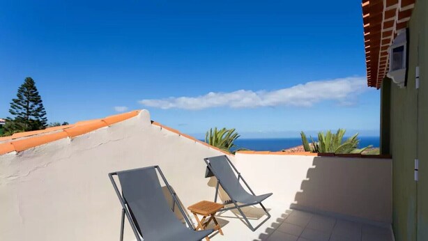 Une terrasse sur le toit, avec deux chaises longues et une petite table, d’où l’on peut admirer un paysage côtier.