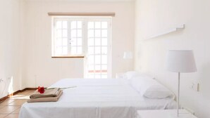 Une chambre d’hôtel avec un grand lit, une table de chevet, une lampe et une fenêtre donnant sur un beau paysage.