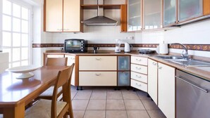 Une cuisine compacte comprenant une table à manger, des chaises, un grille-pain, une bouilloire et un évier.