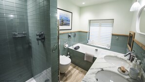Un bany modern amb una dutxa envidriada, una banyera, un lavabo amb taulell de marbre i un vàter.