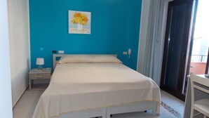 Et hotelværelse med en seng, et natbord, en lampe, en telefon og et vindue med gardiner.