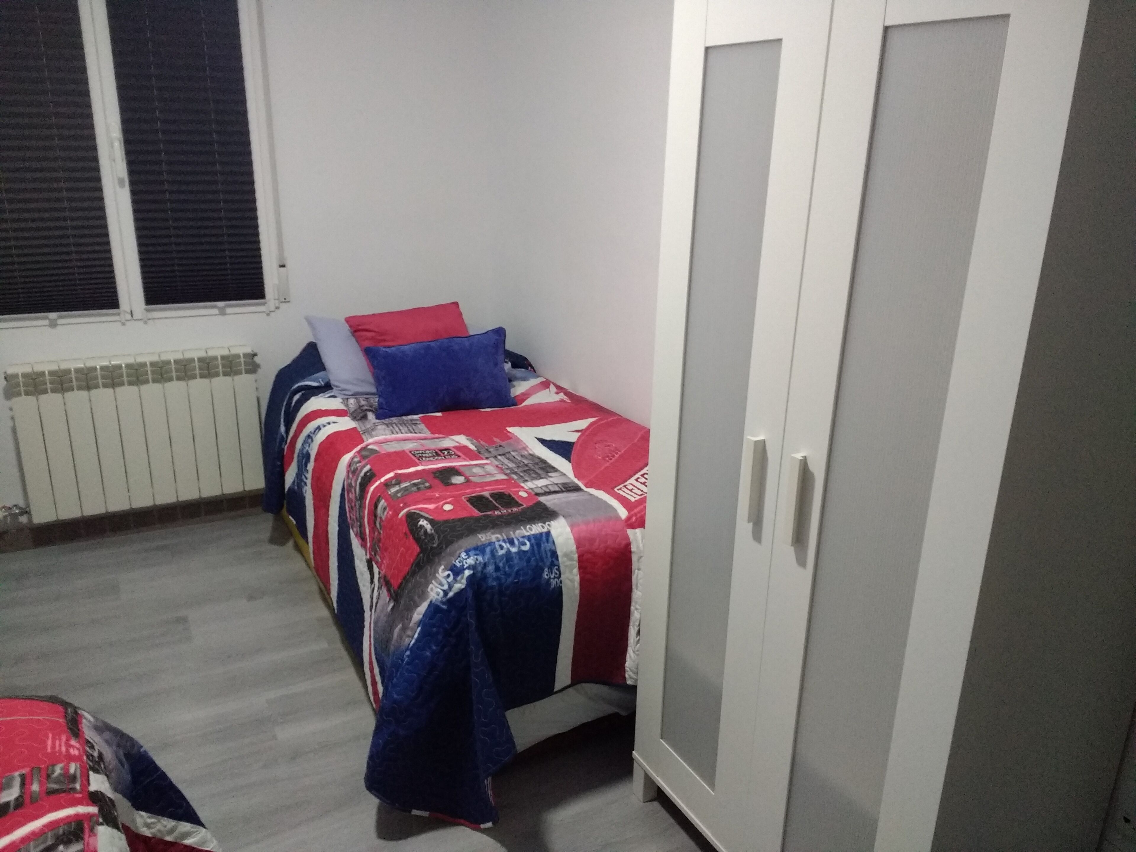 Une chambre à coucher avec un lit, une armoire et un radiateur.