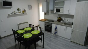 Una cocina compacta con una mesa de comedor, sillas, microondas, horno y refrigerador.