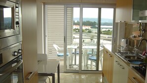 A kitchen with a sliding glass door leading to a balcony with outdoor seating. - Private Condominium, 400 Metres From The Beach, 2 Minutes from Market And Shops  (Sao Martinho do Porto)