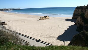 A beach with a clear sky, a sandy shore, and a rocky cliff. - Apartment T2 Sea View - Varandas do Sol (Portimão)