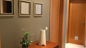 A hallway with a wooden dresser, three framed mirrors, and a potted plant. - Apartment T2 Sea View - Varandas do Sol (Portimão)