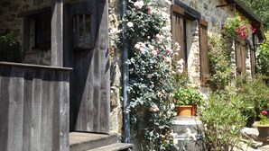 Un bâtiment en pierre avec des volets en bois et un escalier en bois menant à une porte.