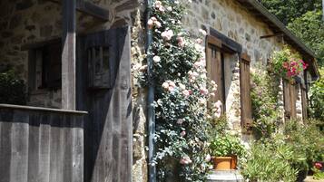 Un bâtiment en pierre avec des volets en bois et un escalier en bois menant à une porte.