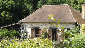 Un bâtiment en pierre avec un toit en pente, des volets en bois et un petit porche.
