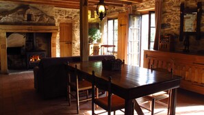 Un intérieur rustique avec une cheminée en pierre, une table en bois et des chaises.
