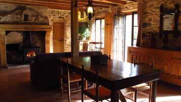 Un intérieur rustique avec une cheminée en pierre, une table en bois et des chaises.
