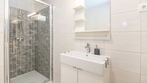 A modern bathroom with a glass-enclosed shower, a white sink with a soap dispenser, and a mirror above the sink. - Cosy studio Stone for 2 with large balcony (Bol)