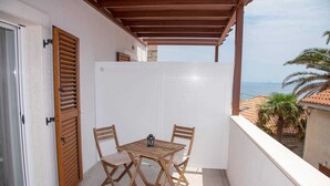 A balcony with a wooden table and chairs, a white door, and a view of the sea. - Cosy studio Stone for 2 with large balcony (Bol)
