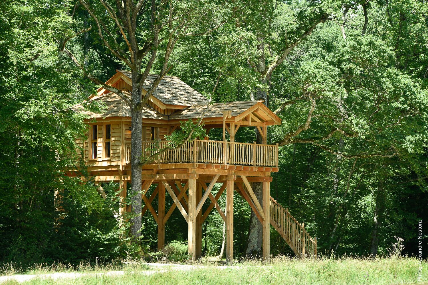 Ein hölzernes Baumhaus mit Balkon und Treppe.