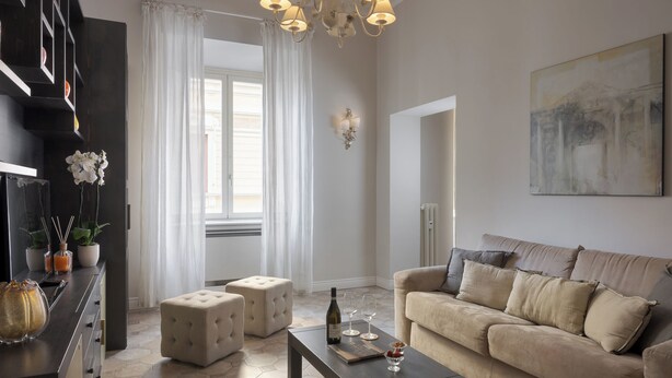 Ein Wohnzimmer mit Sofa, Hocker, Couchtisch und einer Deckenleuchte.