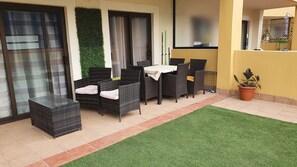 Un patio con muebles de mimbre, una mesita y una planta en maceta.