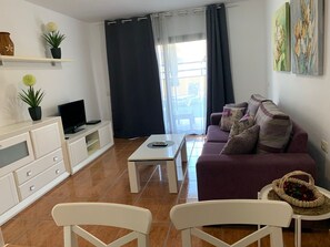 Un salon avec un canapé, des fauteuils, un téléviseur et une table basse.