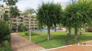 Stroll along the paved pathway to the inviting pool area surrounded by lush greenery and mature trees.