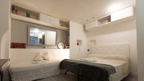 A bedroom with two beds, a large mirror, and built-in shelving. - Rome Studio Historic Center (Roma)