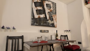 A dining area with a wooden table, chairs, and a wall-mounted artwork. - Rome Studio Historic Center (Roma)
