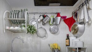 A kitchen with a sink, dish rack, hanging pots and pans, and a spice rack. - Rome Studio Historic Center (Roma)