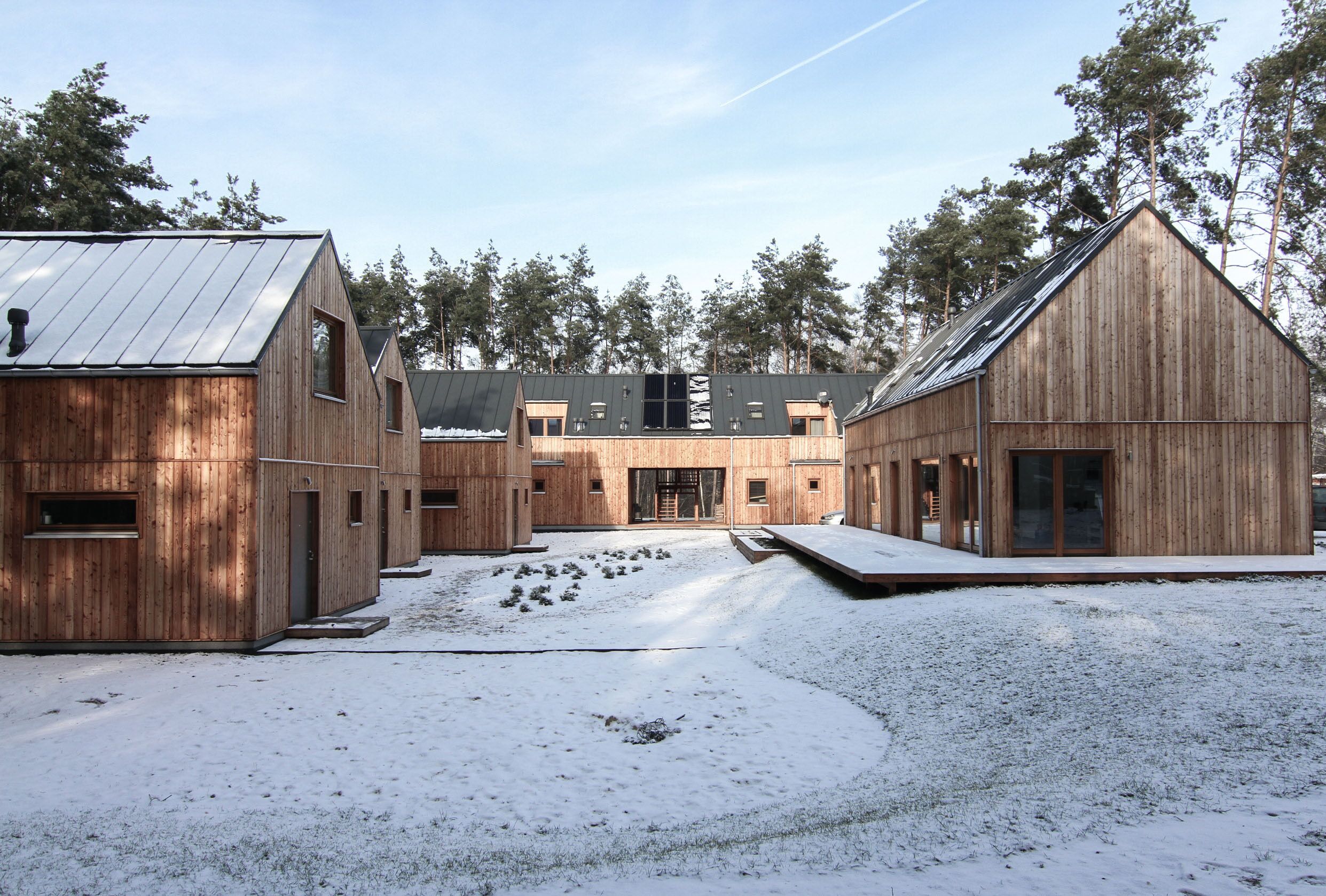 Un complesso di chalet in legno con diversi edifici, una zona esterna coperta e un paesaggio innevato.