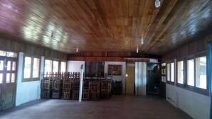 A spacious room with wooden ceiling and walls, large windows, and a central seating area with chairs. - Eco Hotel El Refugio, In the mountains but close to the sea.- ROOM 5 (PLUMA HIDALGO)