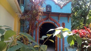 A building with a blue facade, a red archway, and steps leading to a dark entrance. - Eco Hotel El Refugio, In the mountains but close to the sea.- ROOM 5 (PLUMA HIDALGO)