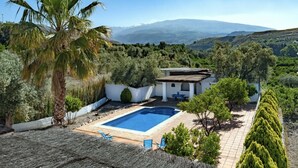 A villa with a swimming pool, surrounded by lush greenery and mountains in the background. - Stunning private rural Villa in the Lecrin Valley, Granada with 7mx4m pool (Melegís)