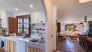 A spacious kitchen with a central island, a dining area with a wooden table and chairs, and a cozy living room with a sofa and a fireplace. - Stunning private rural Villa in the Lecrin Valley, Granada with 7mx4m pool (Melegís)