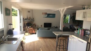 Una cocina moderna con una isla central, una zona de comedor con sofá y televisor.