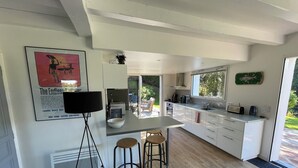 Una cocina moderna con una isla central, taburetes de bar, un amplio ventanal y vistas al exterior.